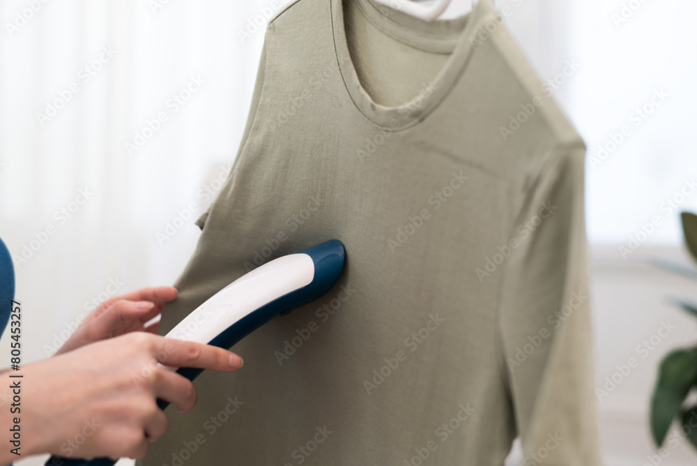 Using steaming iron to ironing t-shirt in home. Doing stream vapor iron for press clothes in hand. 