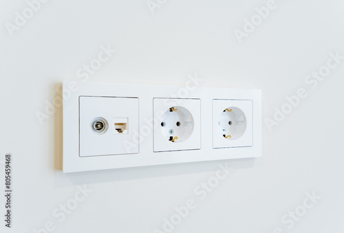 Three white electrical outlets mounted on a white wall