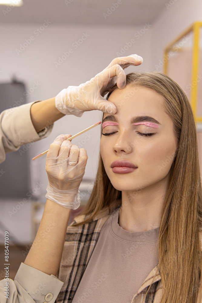 Fototapeta premium Master makes eyebrow correction with wax. Facial hair removal procedure. Soft focus