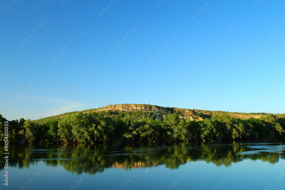 A lake with trees and a hill in the background A lake with trees and a hill in the background