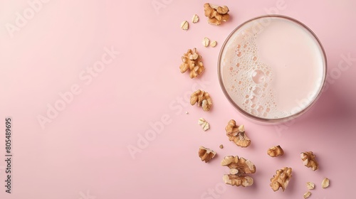  A glass of milk and walnuts in top view, flat lay arrangement on a pink surface