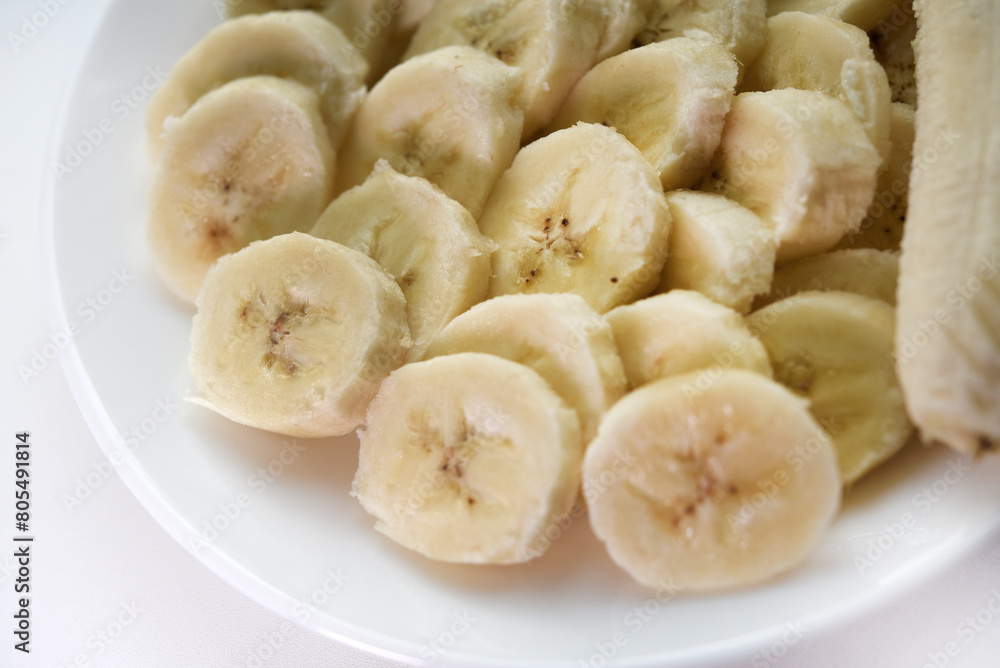 Sliced bananas on a white plate. Delicious and juicy fruits. Breakfast on a plate.