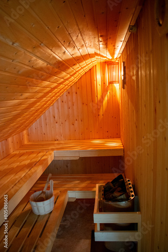 Gemütliche Sauna mit Saunaofen und Hölzernerm Saunakübel mit Holzkelle in warmen Licht. photo