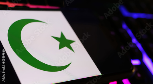 Crescent moon and star islam symbol on smartphone screen with computer keyboard (focus on center of moon)