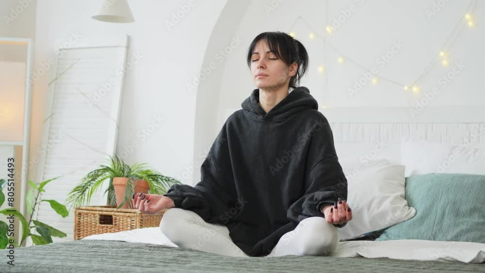 Yoga mindfulness meditation. Young healthy woman practicing yoga in bedroom at home. Woman sitting in lotus pose on bed meditating smiling relaxing indoor. Girl doing breathing practice. Yoga at home Yoga mindfulness meditation. Young healthy woman practicing yoga in bedroom at home. Woman sitting in lotus pose on bed meditating smiling relaxing indoor. Girl doing breathing practice. Yoga at home