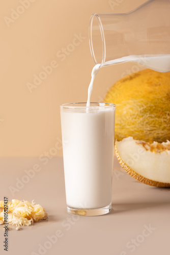 Alternative melon seeds milk and seeds on beige background. Close up. Vertical format. Vegan fruit based milk.