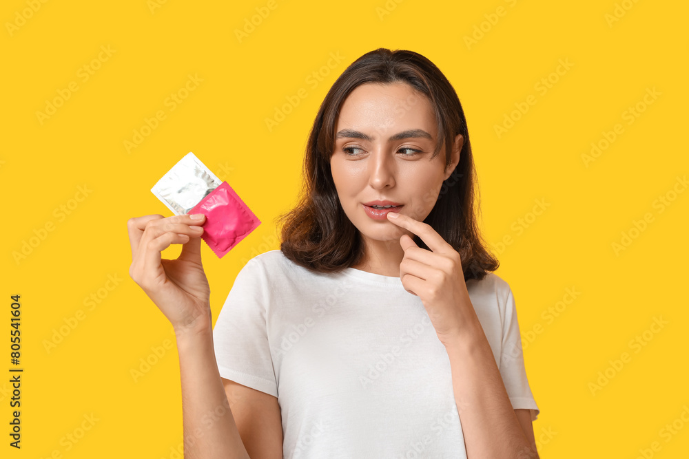 Thoughtful young woman with condoms on yellow background. Safe sex concept Thoughtful young woman with condoms on yellow background. Safe sex concept