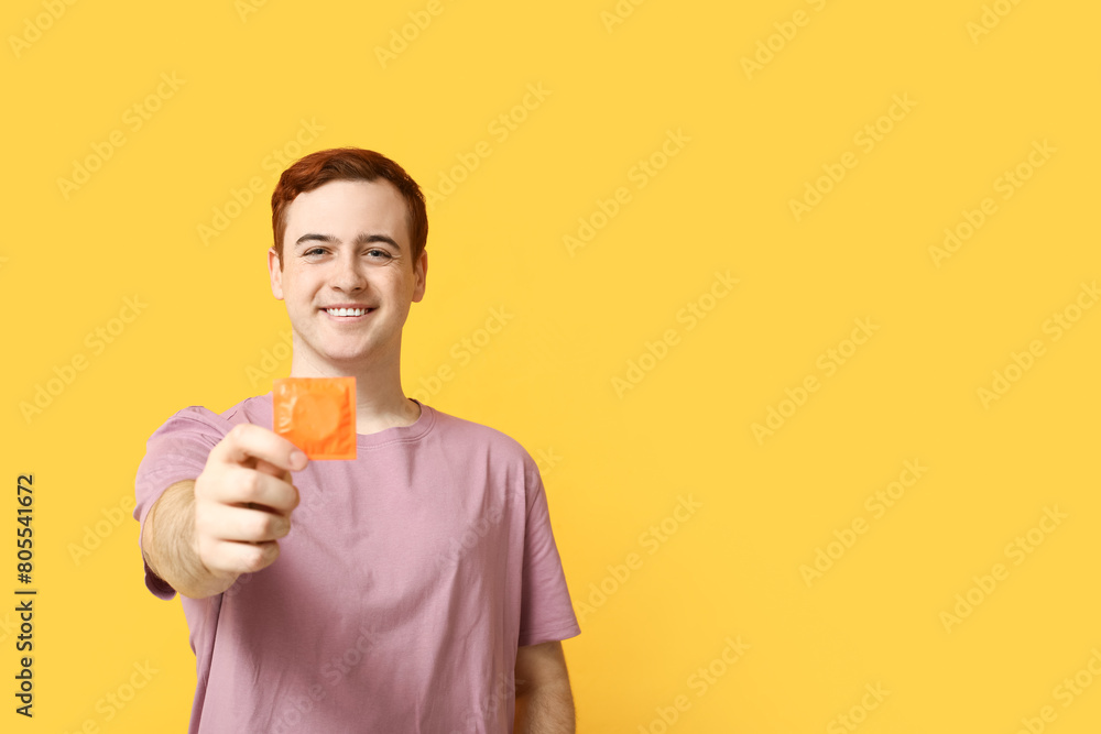 Young man with condom on yellow background. Safe sex concept Young man with condom on yellow background. Safe sex concept