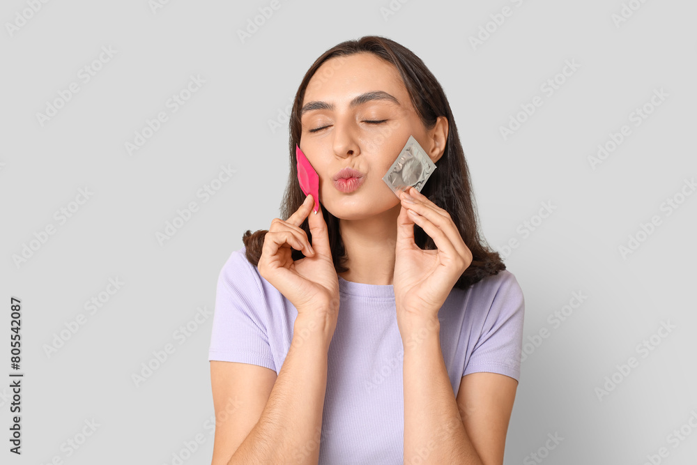 Young woman with condoms on grey background. Safe sex concept Young woman with condoms on grey background. Safe sex concept