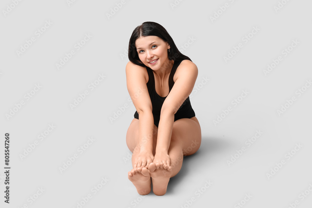 Body positive young woman sitting on light background Body positive young woman sitting on light background