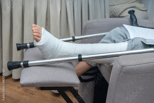 Fotografie Person with broken leg in a plaster cast with crutches at home