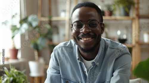 Headshot portrait of happy african American man in glasses sit at desk have video call on gadget, smiling biracial young male in spectacles talk speak on web, using online dating service application