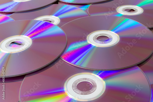Rainbow reflections on a collection of compact discs. Vibrant stack of cds with iridescent reflections creating a spectrum of colors, representing data storage and digital technology.