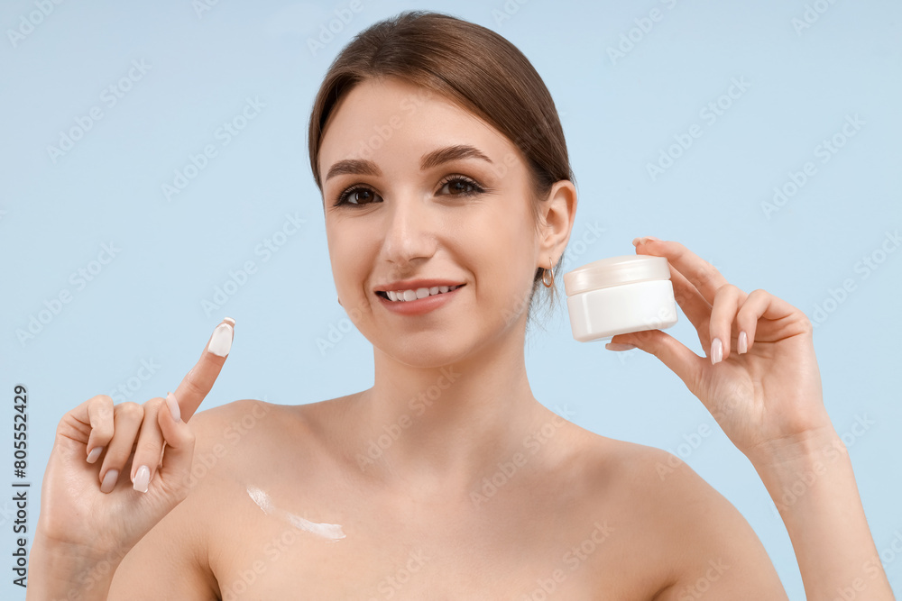 Beautiful young woman with jar of cosmetic cream on blue background Beautiful young woman with jar of cosmetic cream on blue background