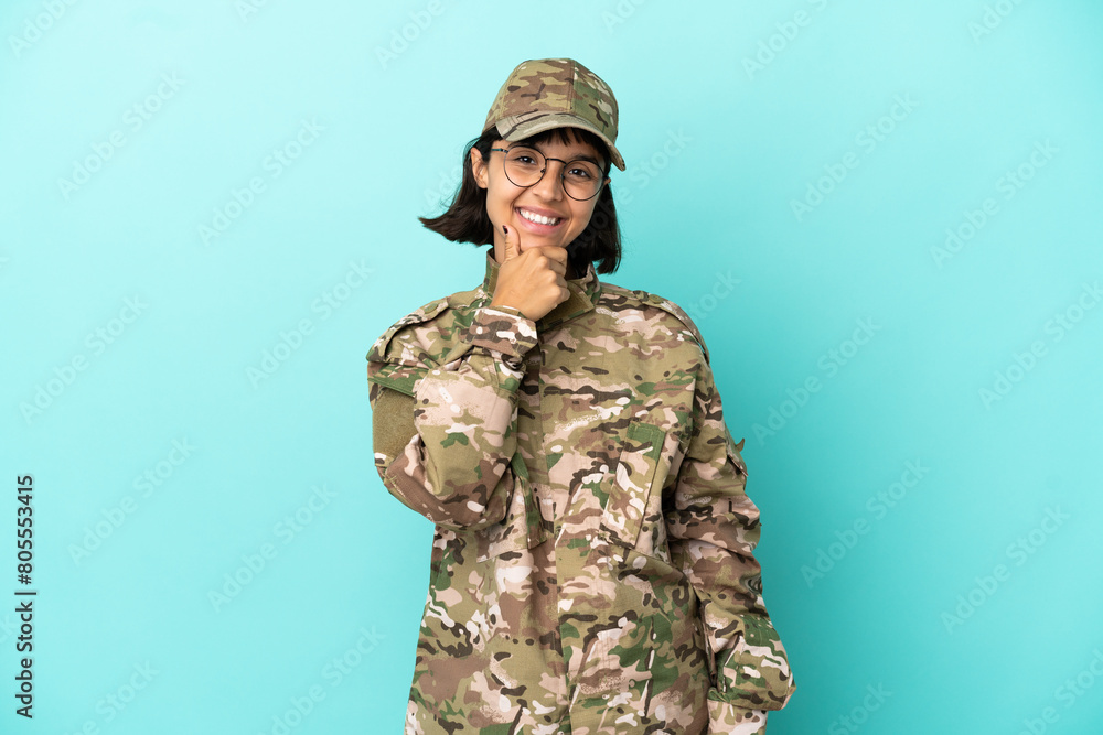 Military mixed race woman isolated on blue background with glasses and smiling Military mixed race woman isolated on blue background with glasses and smiling