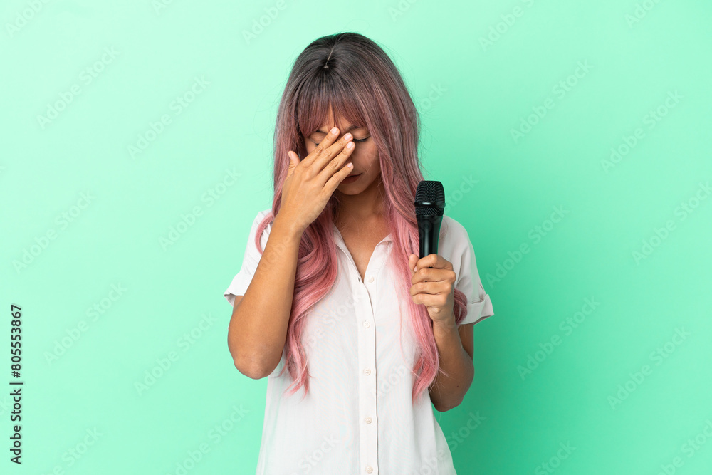 Young mixed race singer woman with pink hair isolated on green background with tired and sick expression Young mixed race singer woman with pink hair isolated on green background with tired and sick expression