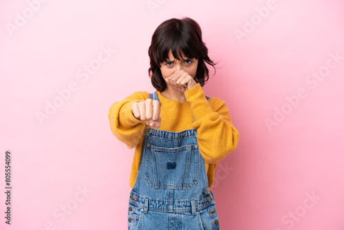 Young woman with overalls isolated background with fighting gesture
