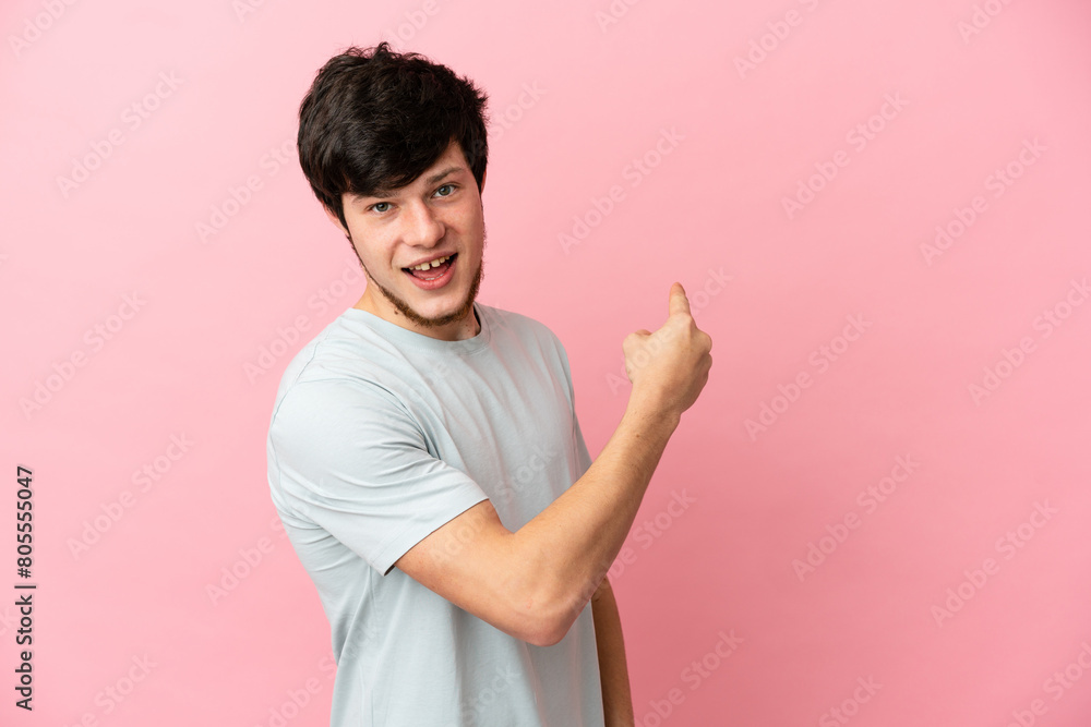 Young Russian man isolated on pink background pointing back Young Russian man isolated on pink background pointing back