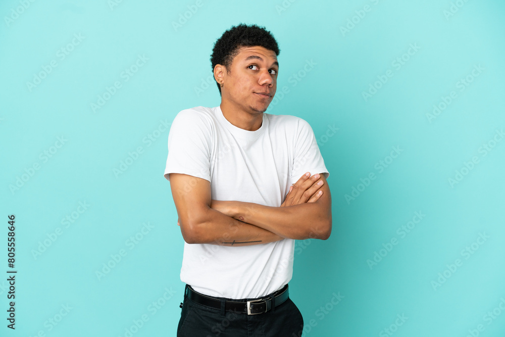 Young African American man isolated on blue background making doubts gesture while lifting the shoulders Young African American man isolated on blue background making doubts gesture while lifting the shoulders