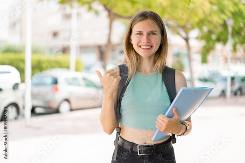 Free Download Young blonde student woman at outdoors pointing to the side to present a product - GFXLoad