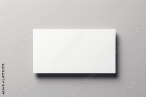 A simple blank white rectangular box or panel placed horizontally on a gray marble surface, casting a soft shadow beneath. photo