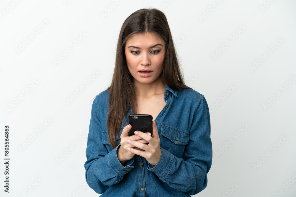 Young caucasian woman isolated on white background looking at the camera while using the mobile with surprised expression Young caucasian woman isolated on white background looking at the camera while using the mobile with surprised expression