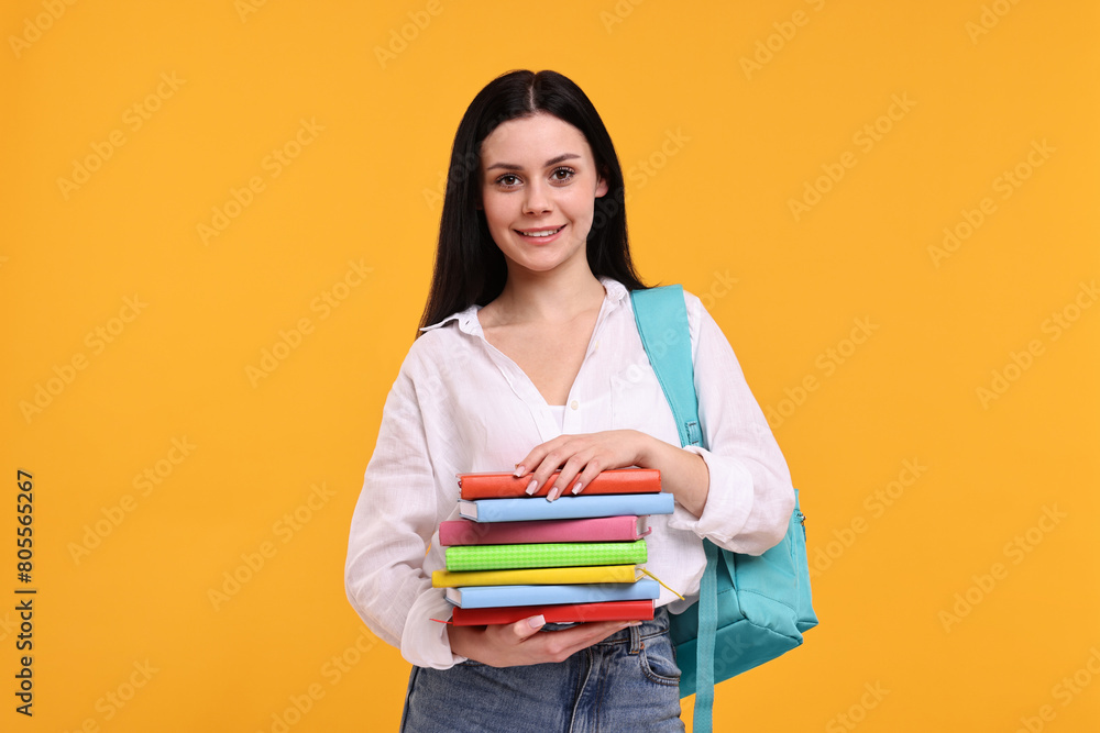 Smiling student with stack of books on yellow background Smiling student with stack of books on yellow background