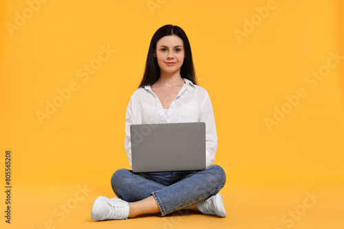 Student with laptop sitting on yellow background © New Africa