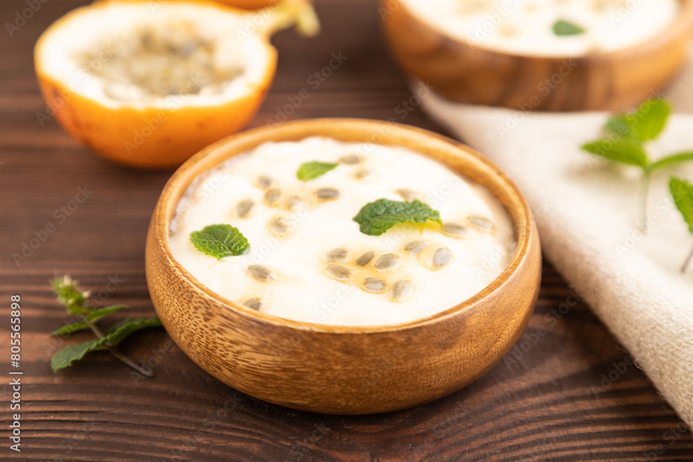 Yoghurt with granadilla and mint in wooden bowl on brown wooden, side view, selective focus. Yoghurt with granadilla and mint in wooden bowl on brown wooden, side view, selective focus.