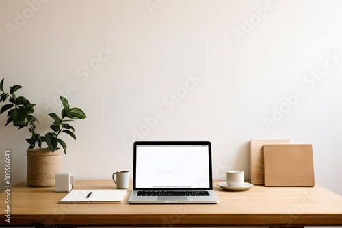 A minimalist workspace featuring a laptop with a black screen, a desk lamp, a vase with white flowers, books, and stationery on a wooden desk against a light beige wall. © SaroStock