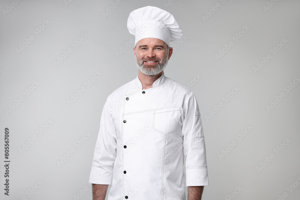 Happy chef in uniform on grey background