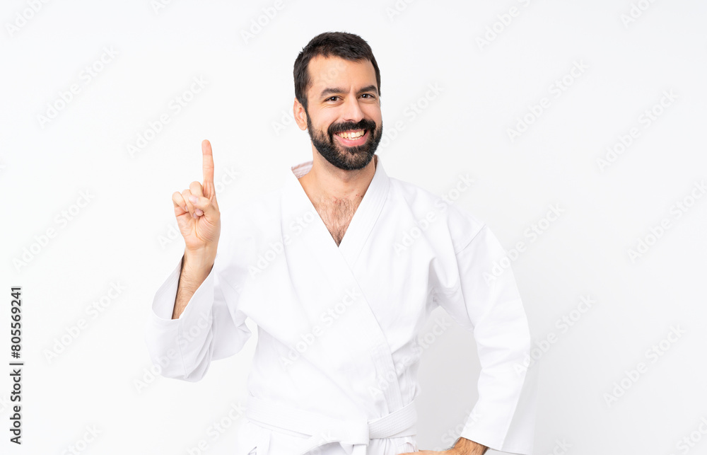 Young man doing karate over isolated white background showing and lifting a finger in sign of the best Young man doing karate over isolated white background showing and lifting a finger in sign of the best