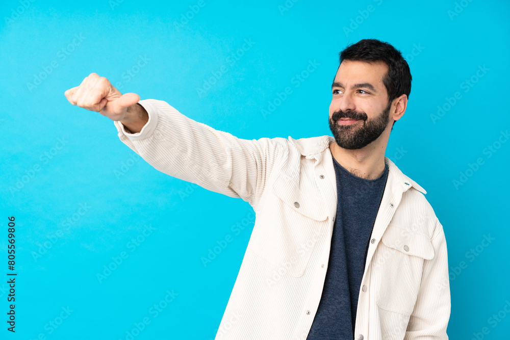 Young handsome man with white corduroy jacket over isolated blue background giving a thumbs up gesture Young handsome man with white corduroy jacket over isolated blue background giving a thumbs up gesture