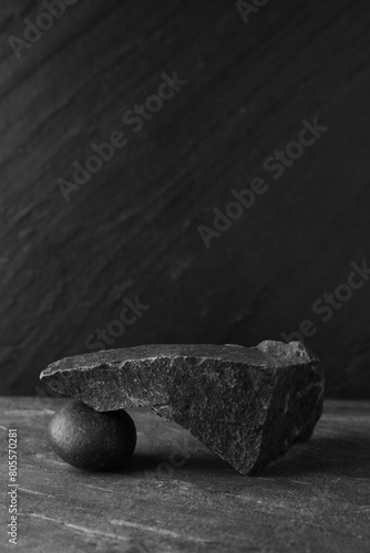 Presentation for product. Podium made of different stones on grey textured background. Space for text
