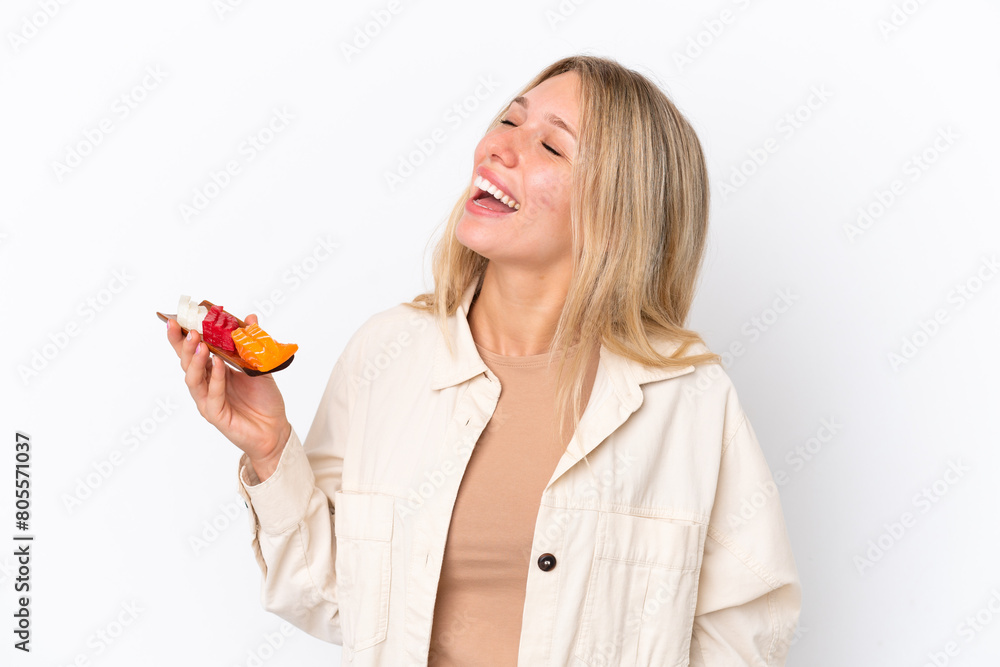 Young caucasian woman holding sashimi isolated on white background laughing in lateral position Young caucasian woman holding sashimi isolated on white background laughing in lateral position