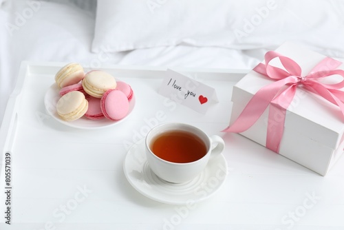 Tasty breakfast served in bed. Delicious eclairs, tea, gift box and I Love You card on tray