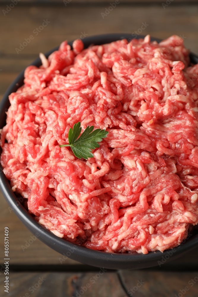 Raw ground meat and parsley in bowl on wooden table, closeup Raw ground meat and parsley in bowl on wooden table, closeup
