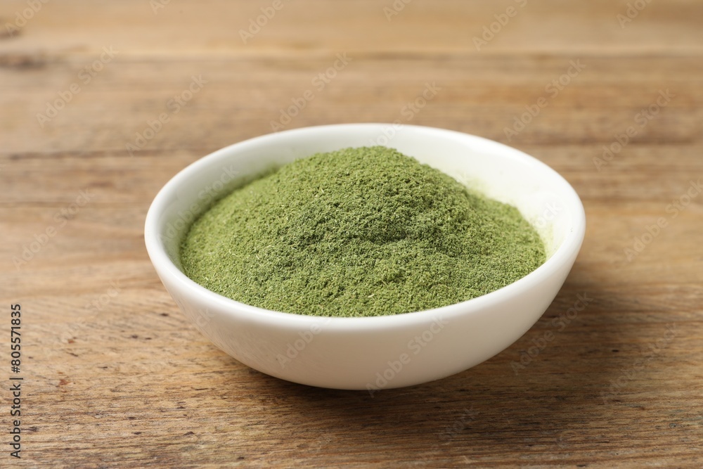Wheat grass powder in bowl on wooden table, closeup Wheat grass powder in bowl on wooden table, closeup