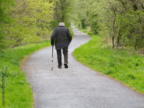 Elderly man walking alone on path in the countryside