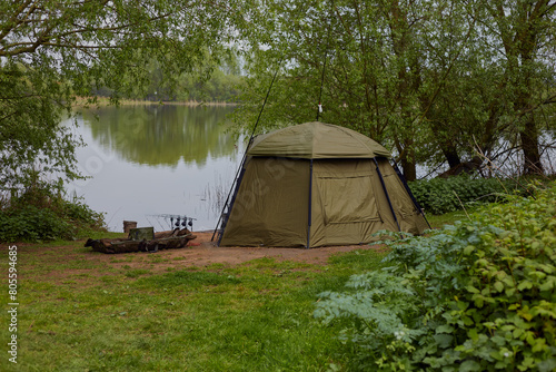 Landscape image of a lake view with a carp anglers equipment set up fishing. © Mark