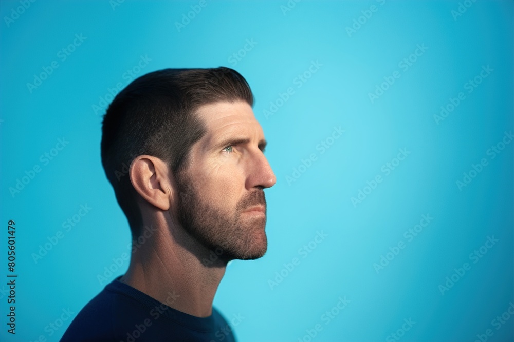 Fototapeta premium A man with a beard and a blue shirt is looking up at the sky