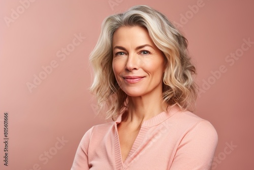 A woman with a pink shirt and blonde hair is smiling