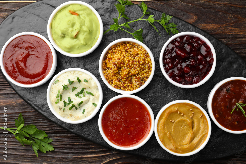 Different tasty sauces in bowls and parsley on wooden table, top view Different tasty sauces in bowls and parsley on wooden table, top view