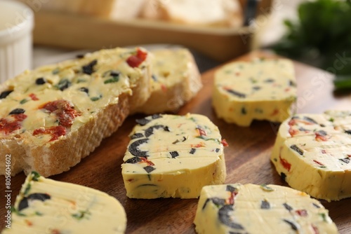 Tasty butter with olives, chili pepper, parsley and bread on table, closeup