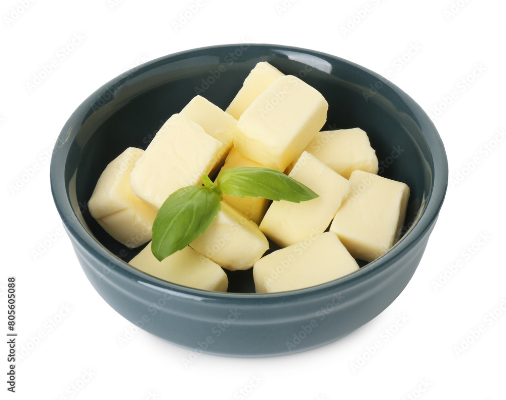 Tasty butter cubes and basil leaves in bowl isolated on white