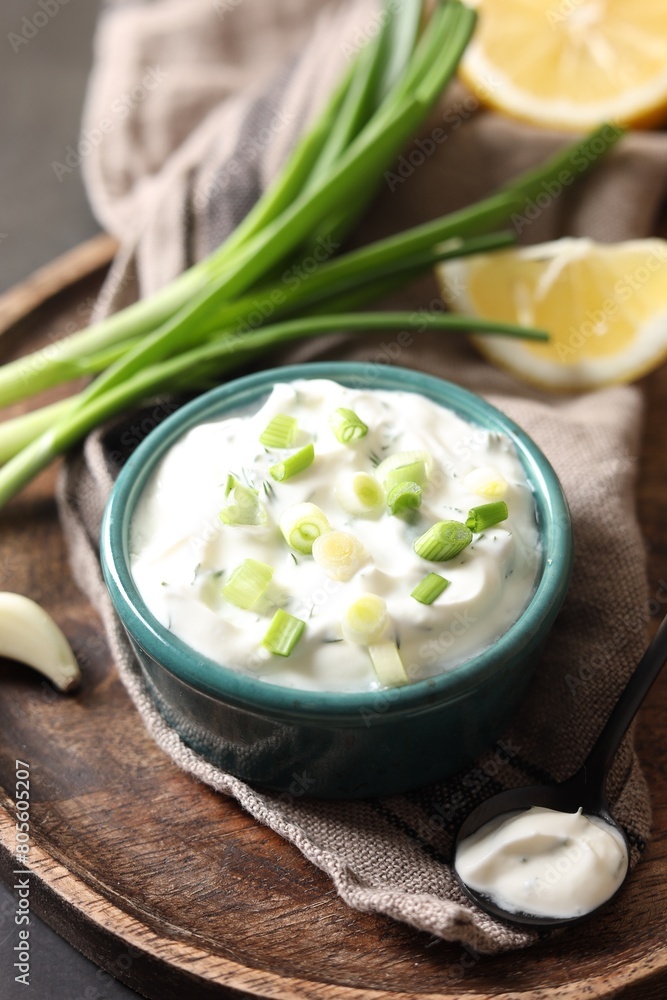 Delicious yogurt in bowl, green onion and spoon on table Delicious yogurt in bowl, green onion and spoon on table