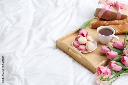 Delicious breakfast, flowers, gift box and card with phrase I Love You on bed, space for text