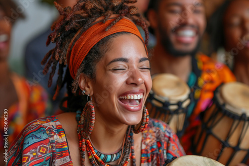 A cheerful black woman in traditional dress laughs and plays music with several people. photo