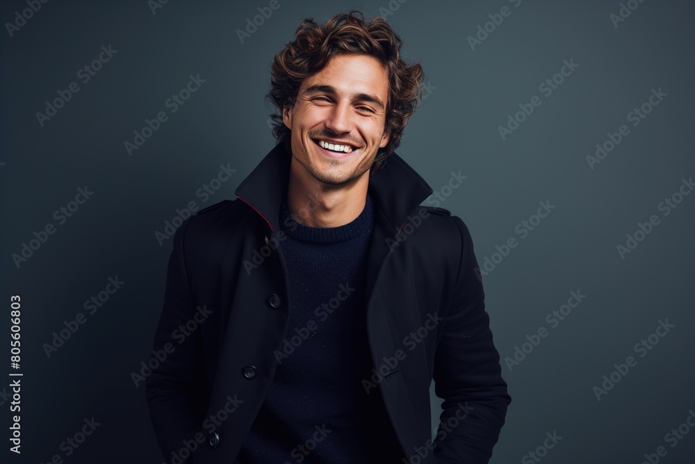 A man in a black coat and blue sweater is smiling A man in a black coat and blue sweater is smiling
