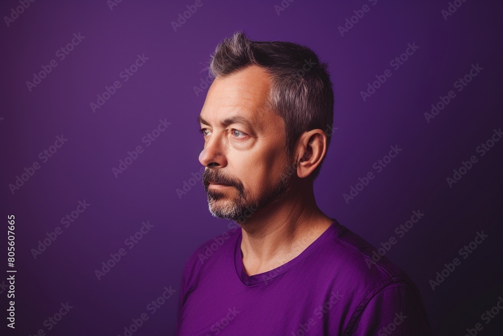 Fototapeta premium A man with a beard and gray hair is wearing a purple shirt